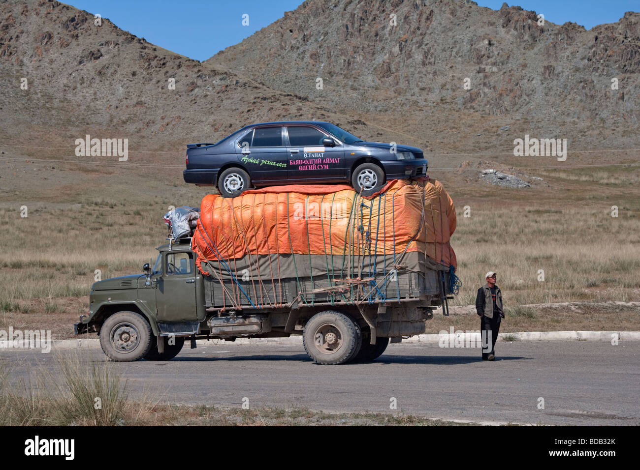 Mongolian man hauls his lottery winnings (an automobile) from Ulaan Baatar to far western Mongolia on top of a truck Stock Photo