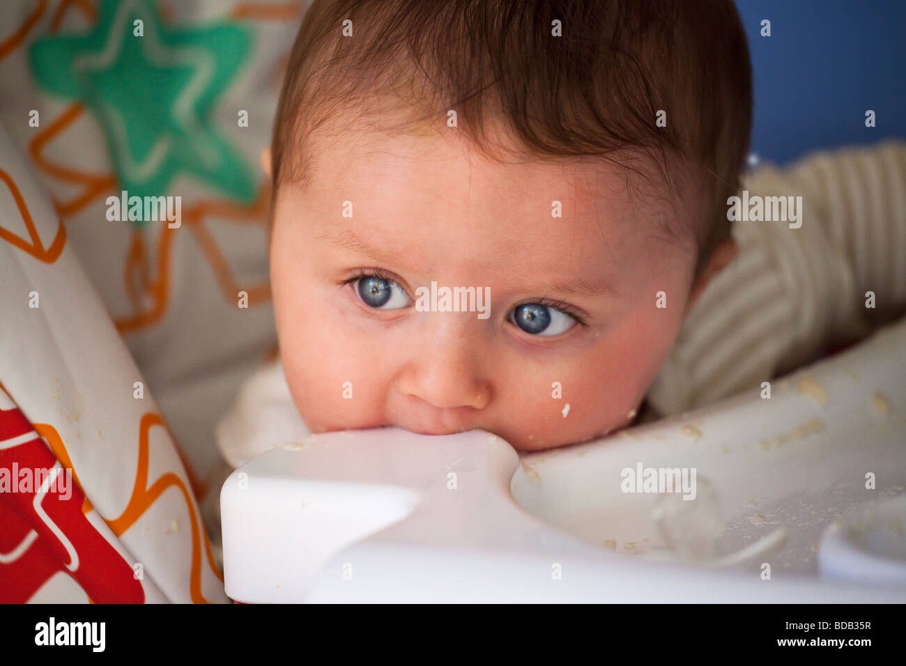 young baby under one year old making a mess with food while trying to