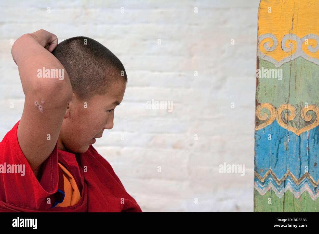 Young Buddhist monk scratches his head while awaiting a ceremony at Erdene Zuu monastery, north central Mongolia Stock Photo