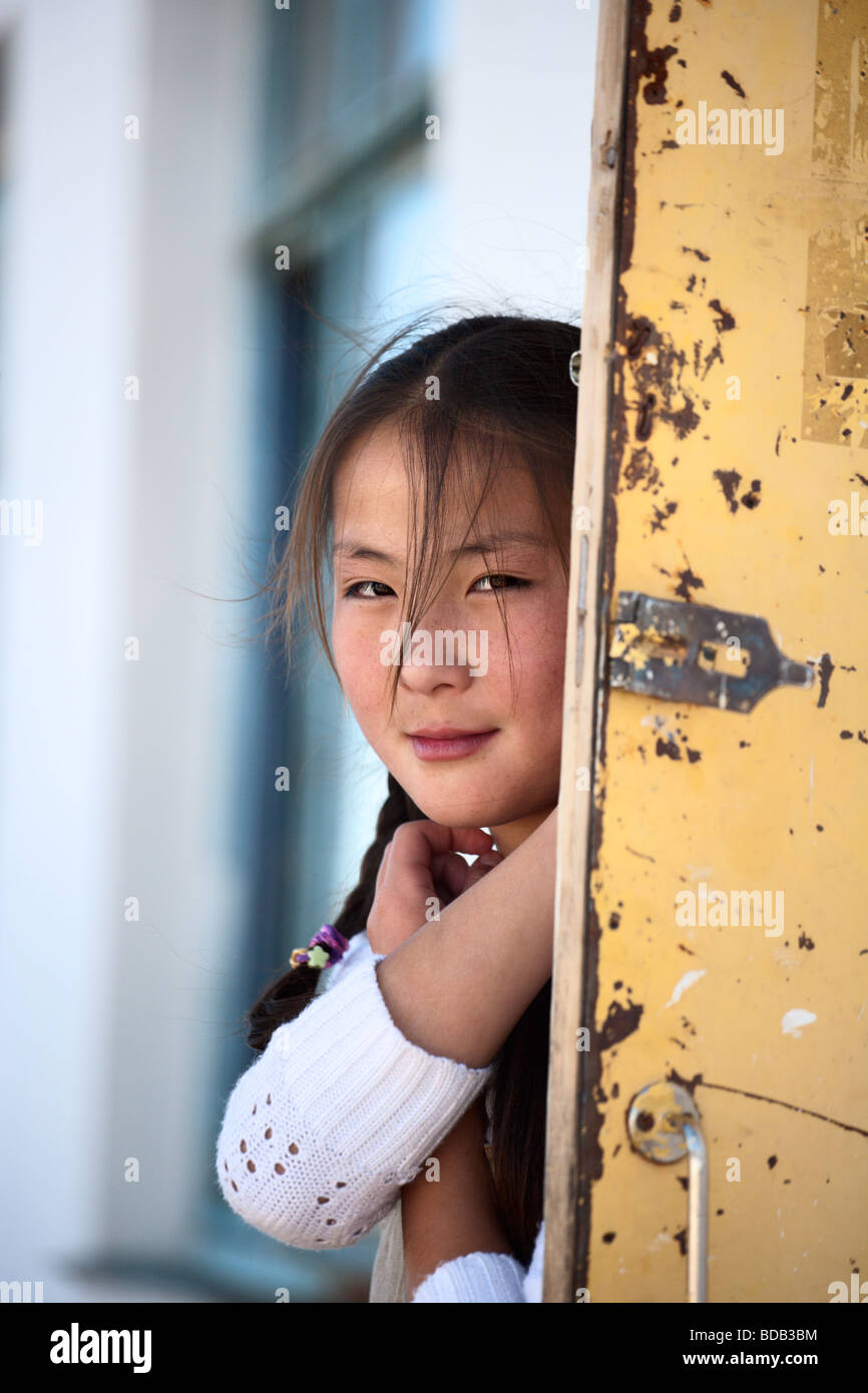 Teenage Mongolian beauty peeks around a steel door, north central Mongolia Stock Photo