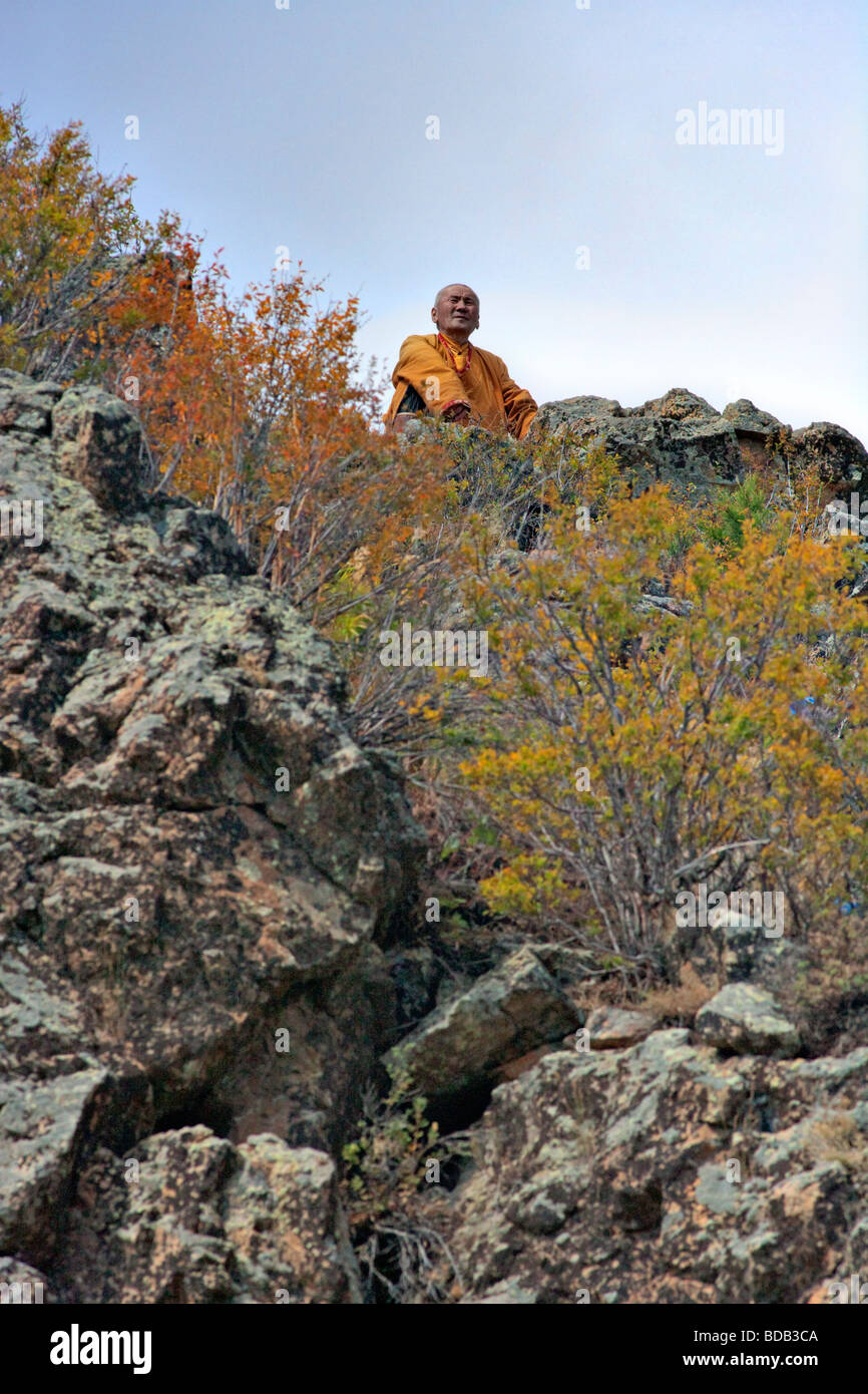 Mongolian Buddhist monk meditates atop a rocky promontory, north central Mongolia Stock Photo
