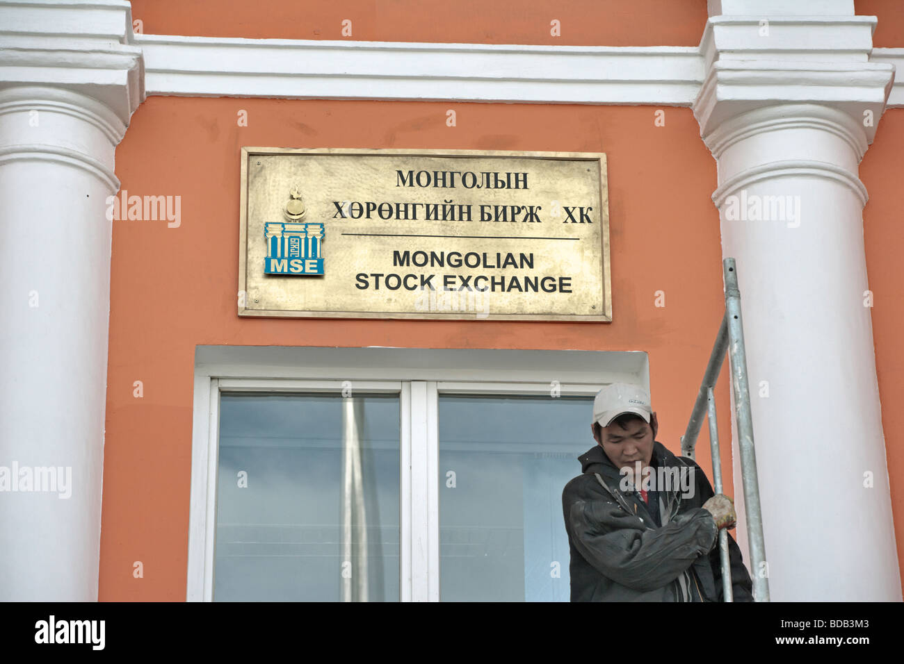 Bright brass sign for the Mongolian Stock Exchange with a contrasting workman, Ulaan Baatar, Mongolia Stock Photo