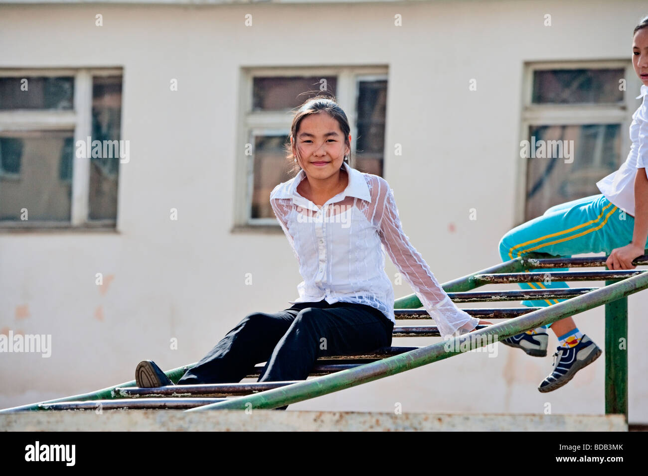 Lovely young Mongolian schoolgirls play on the playground equipment, Ulaan Baatar, Mongolia Stock Photo