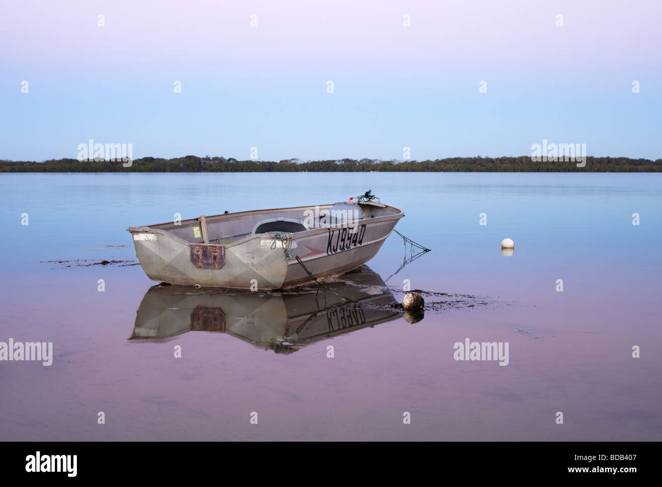 A small fishing boat anchored in still calm water Stock Photo - Alamy