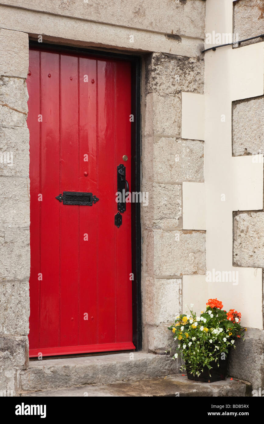 Red wooden door with wrought iron handle at entrance to a house with stone doorstep. UK Britain Stock Photo