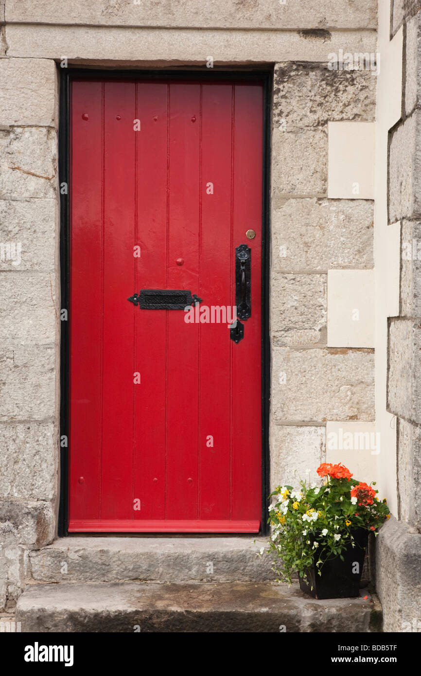 Red wooden front door with wrought iron handle at entrance to a house with stone doorstep. UK Britain Stock Photo