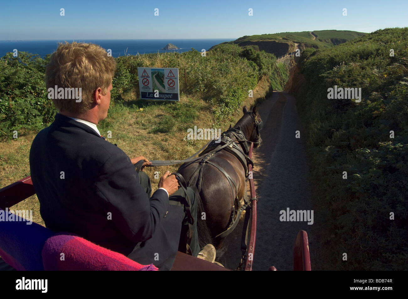 Horse carriage approaching the narrow isthmus of La Coupée, Island of Sark, Channel Islands Stock Photo