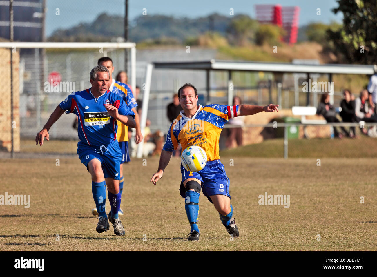 Two soccer teams playing a match heading the ball dribbling and kicking Stock Photo