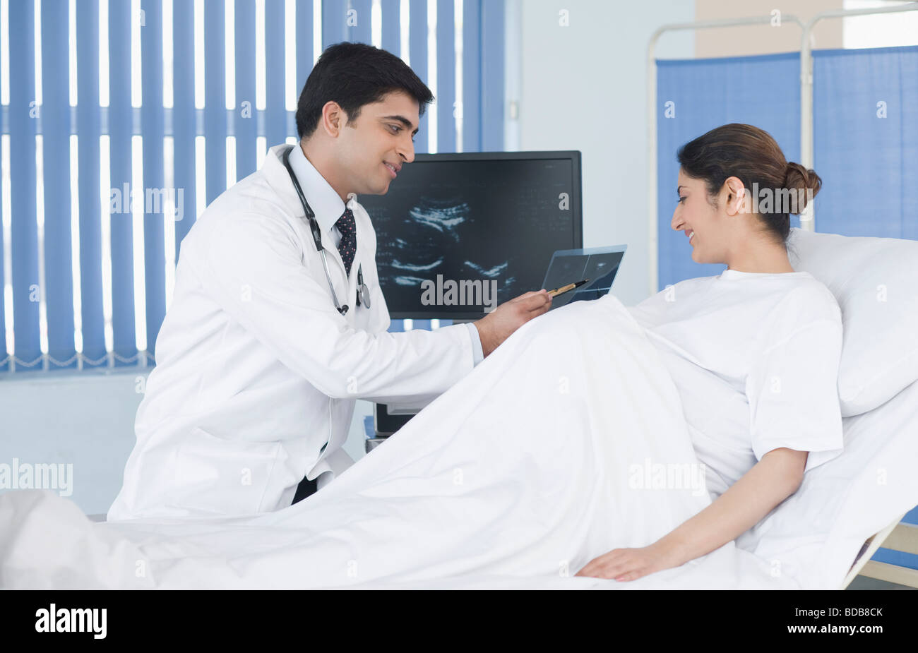 Male doctor showing ultrasound to pregnant woman Stock Photo - Alamy