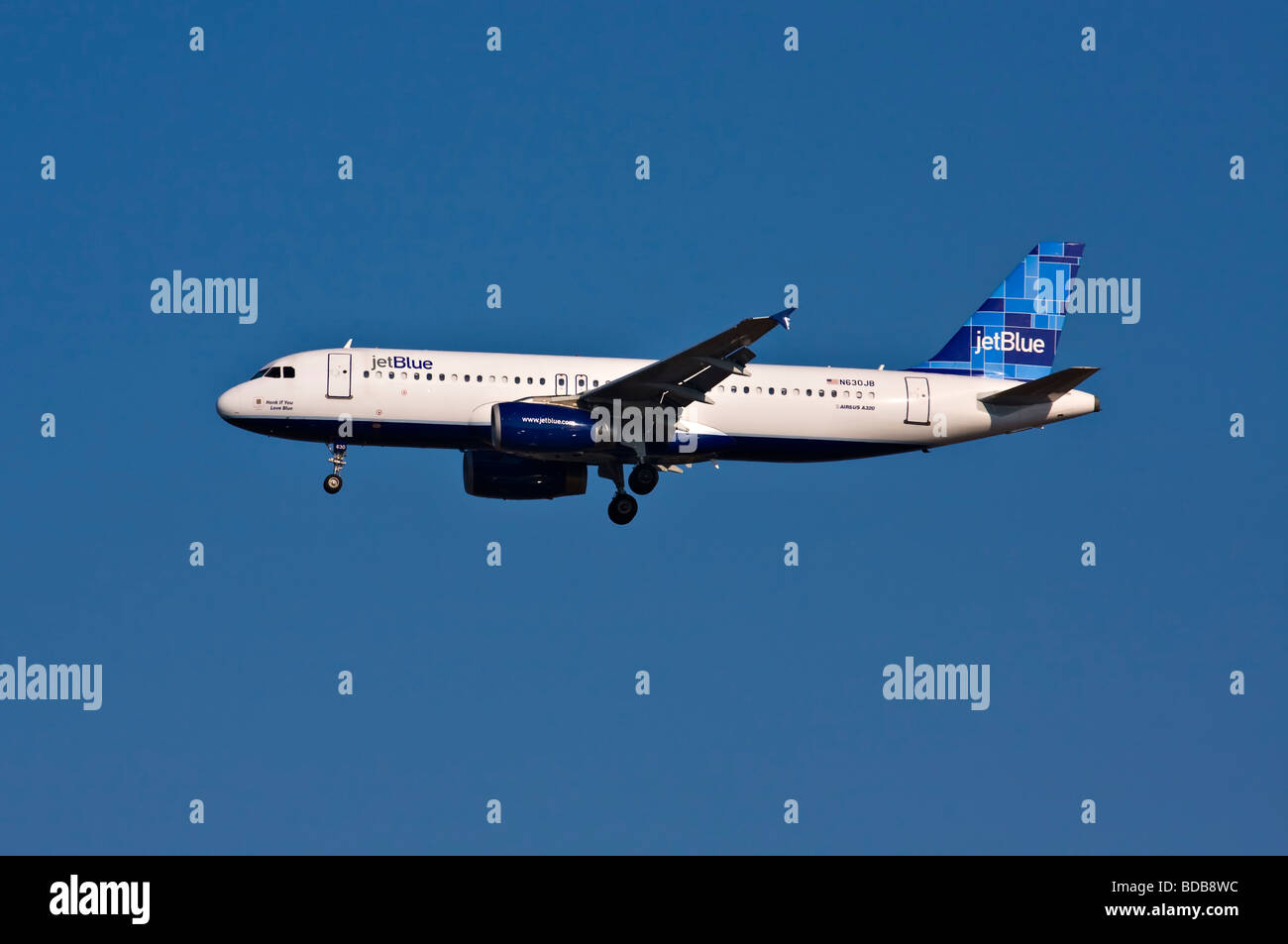 jetBlue Airbus A320 in flight with landing gear down.  'Honk If You Love Blue' written on the nose. Stock Photo