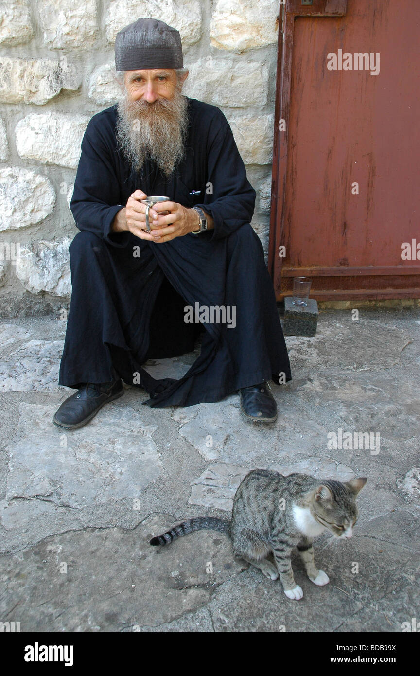 A Serbian Orthodox monk posing for a picture with his cat, on an island ...