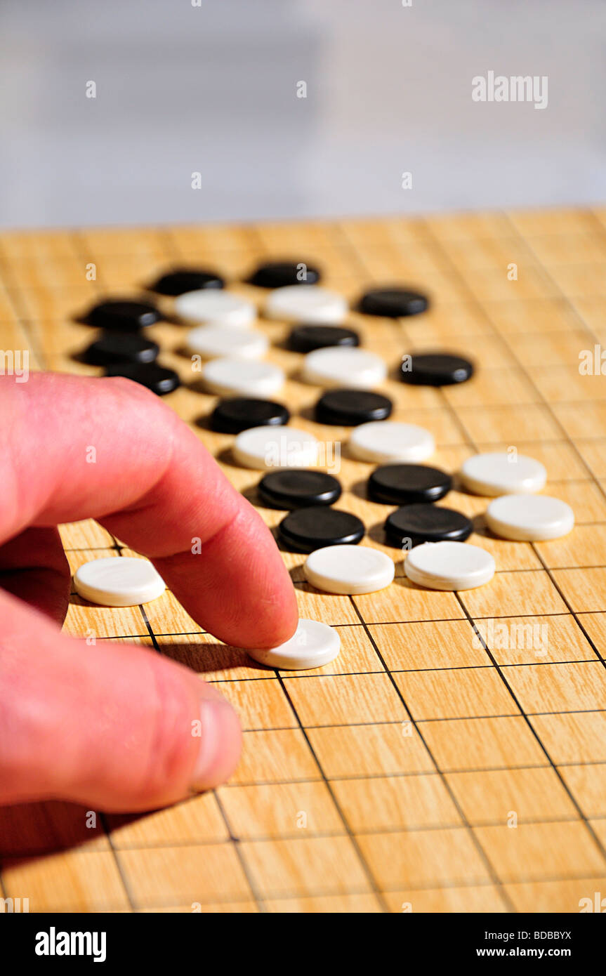 go game with hand pushin pieces Stock Photo - Alamy