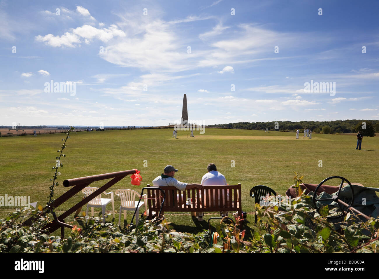 Spectators watch a village cricket match in the shadow of the Bilsington Monument Bilsington Kent Stock Photo