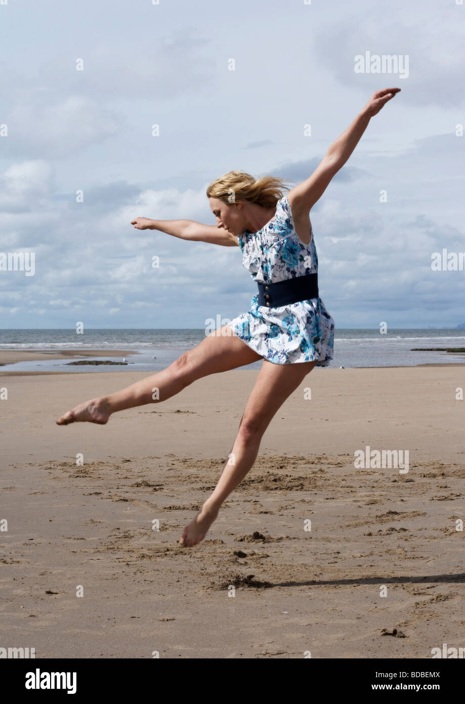 Woman dancing on the beach wearing an old-fashioned floral dress Stock Photo