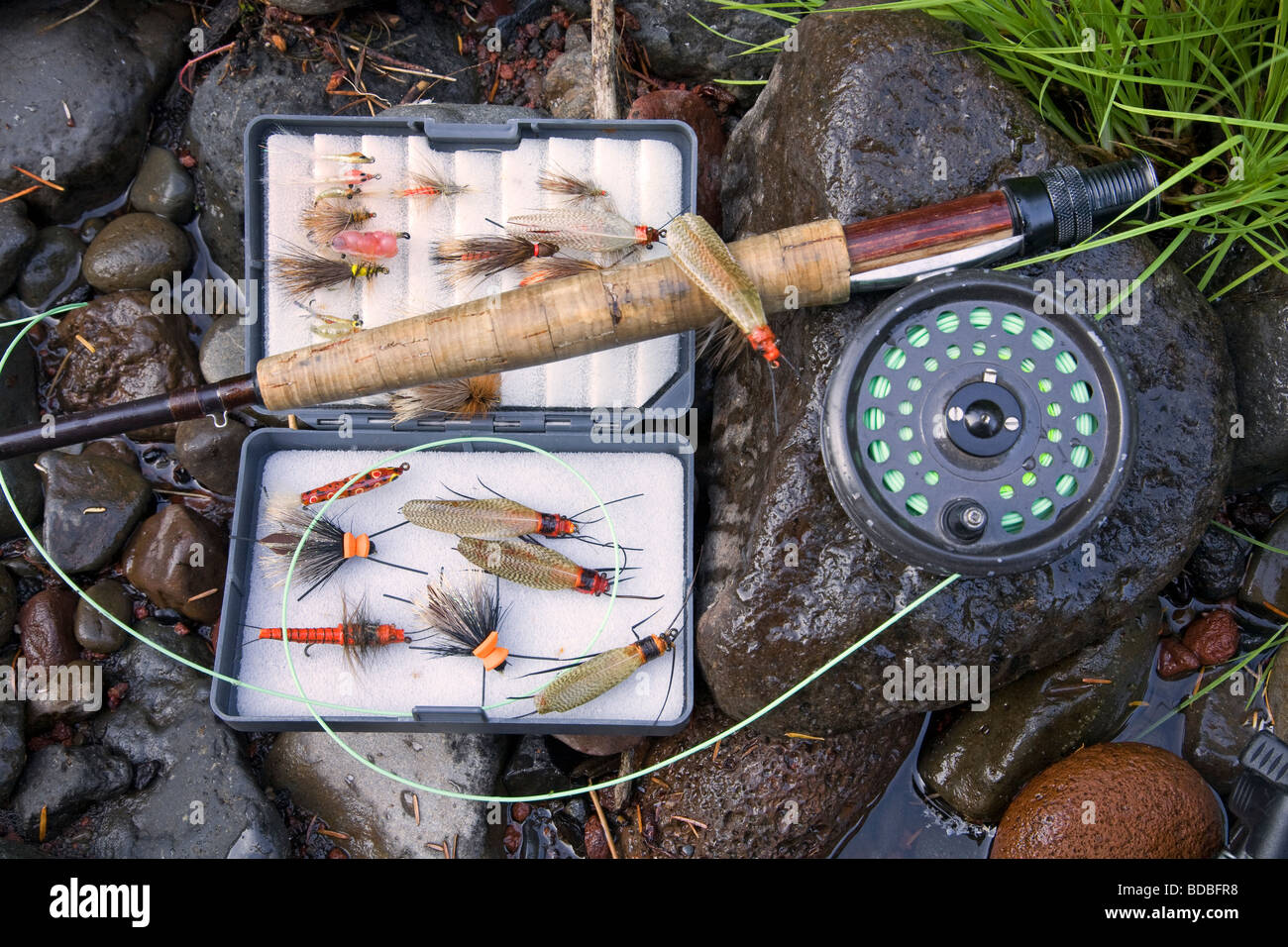 A fly rod, fly reel, trout fishing net, and box of artificial flies used for fly fishing for trout and steelhead Stock Photo