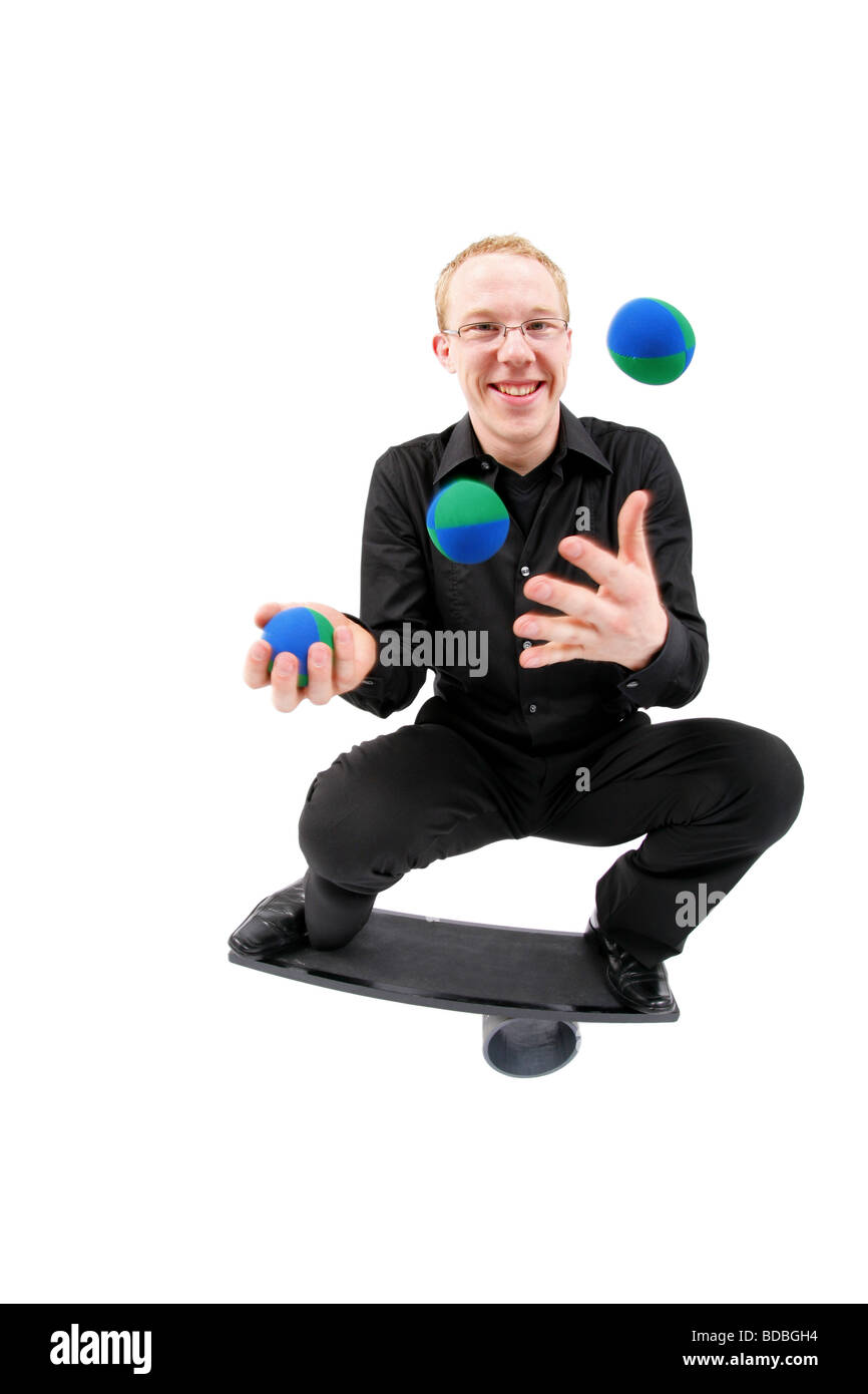 young man juggling with balls and balancing on a rola bola balance