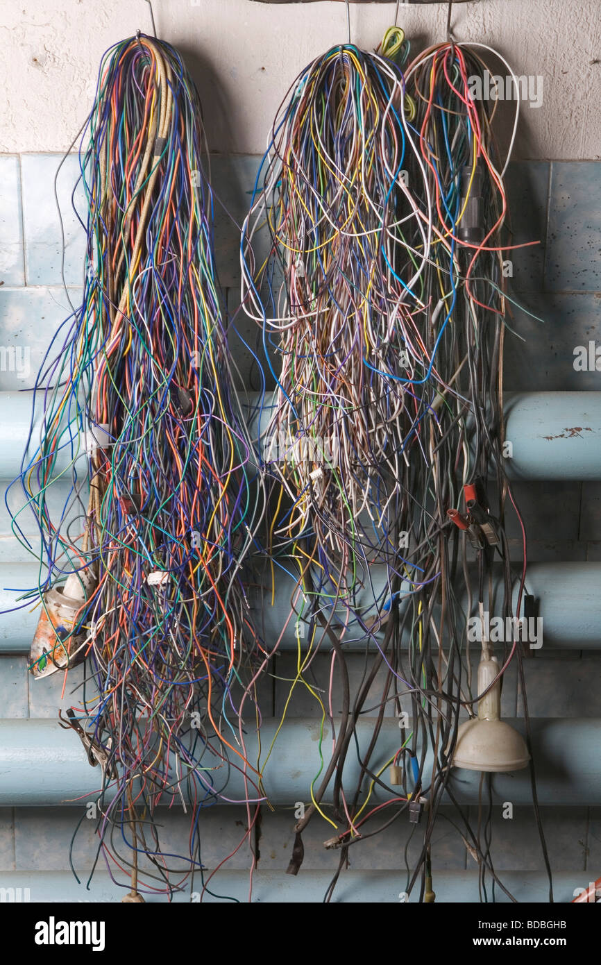 multitude of cables hanging on wall in workshop Stock Photo