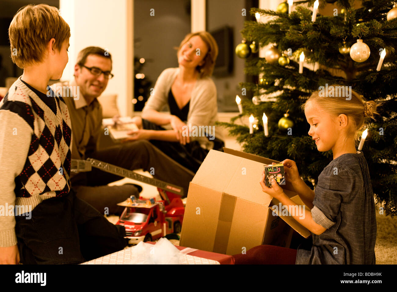 parents watching their children opening christmas presents on christmas