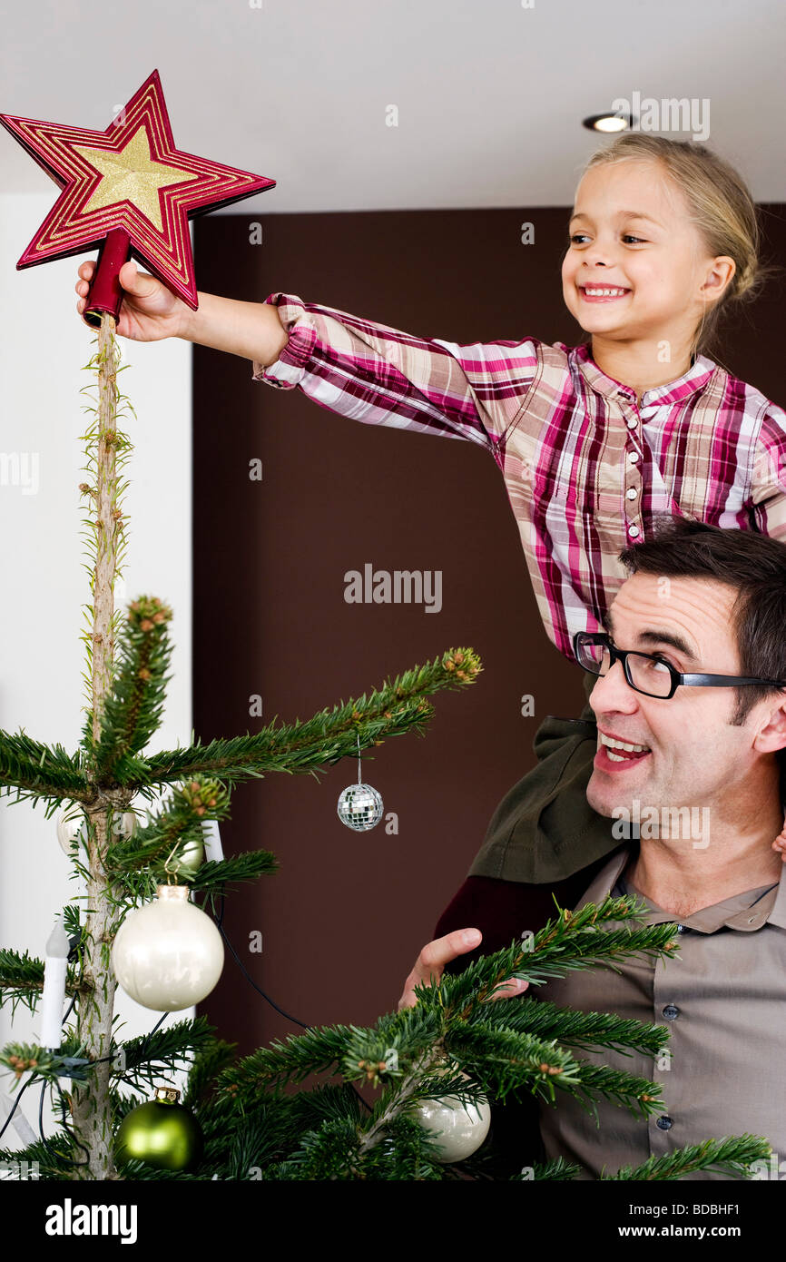 young girl putting star on top of christmas tree Stock Photo Alamy