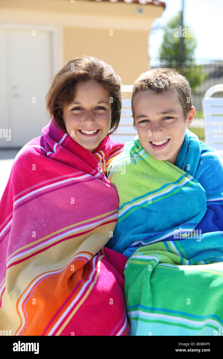 Two kids wrapped in towels by pool Stock Photo