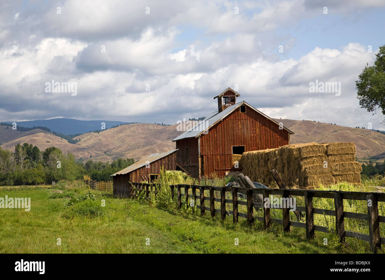 An old red barn and haystack on a ranch near Halfway Oregon on the slopes of the Wallowa Mountains in eastern Oregon Stock Photo