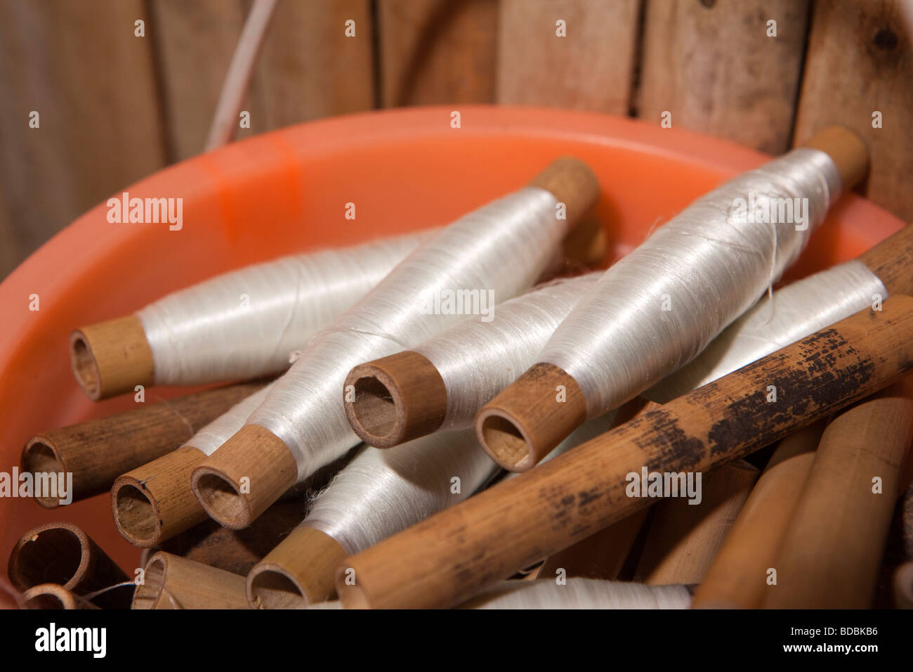 Indonesia Sulawesi Sengkang small local silk weaving workshop bobbins wound with white thread Stock Photo