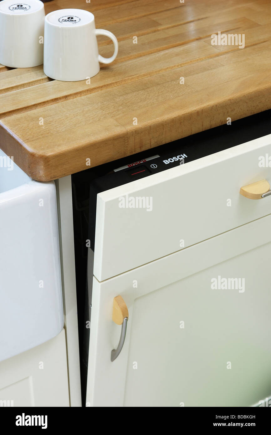 Close up of white cups on worktop above white dishwasher with door open Stock Photo