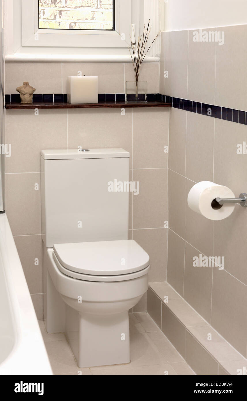 Close up of modern white toilet in beige tiled bathroom Stock Photo