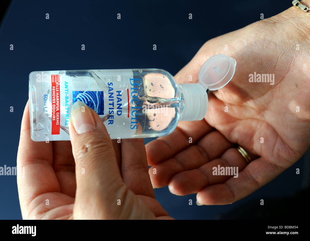 Woman squeezing out Bioclens hand sanitiser gel onto hands to prevent possible virus infection especially from Swine Flu Stock Photo