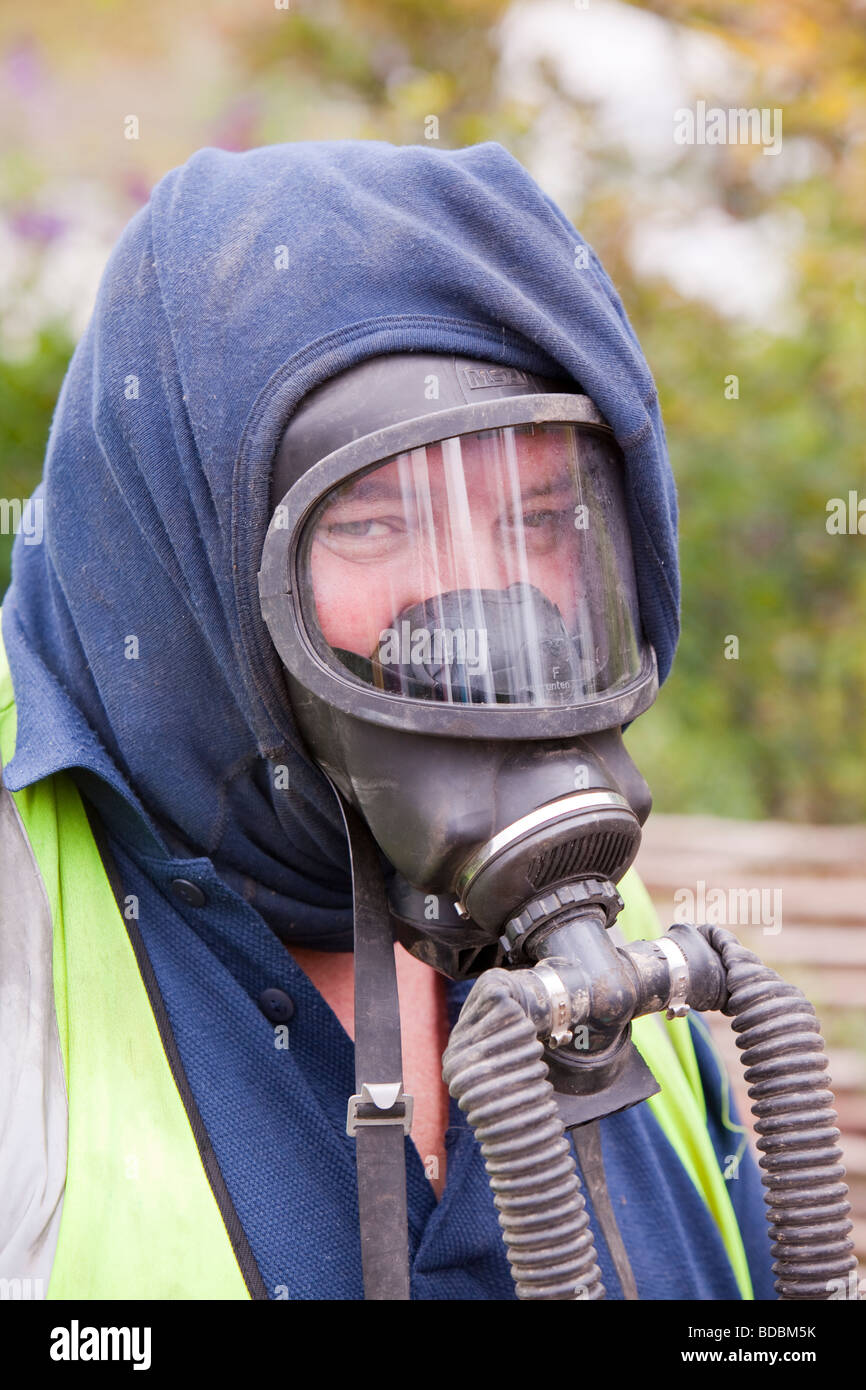 A Britiush Gas worker wears protective gas mask prior to cutting through the gas main as part of an upgrade of piping Stock Photo