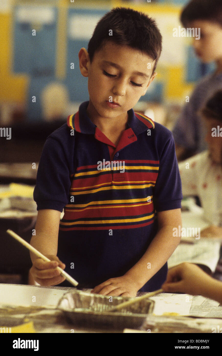 1st Grade Hispanic boy painting in art class Stock Photo