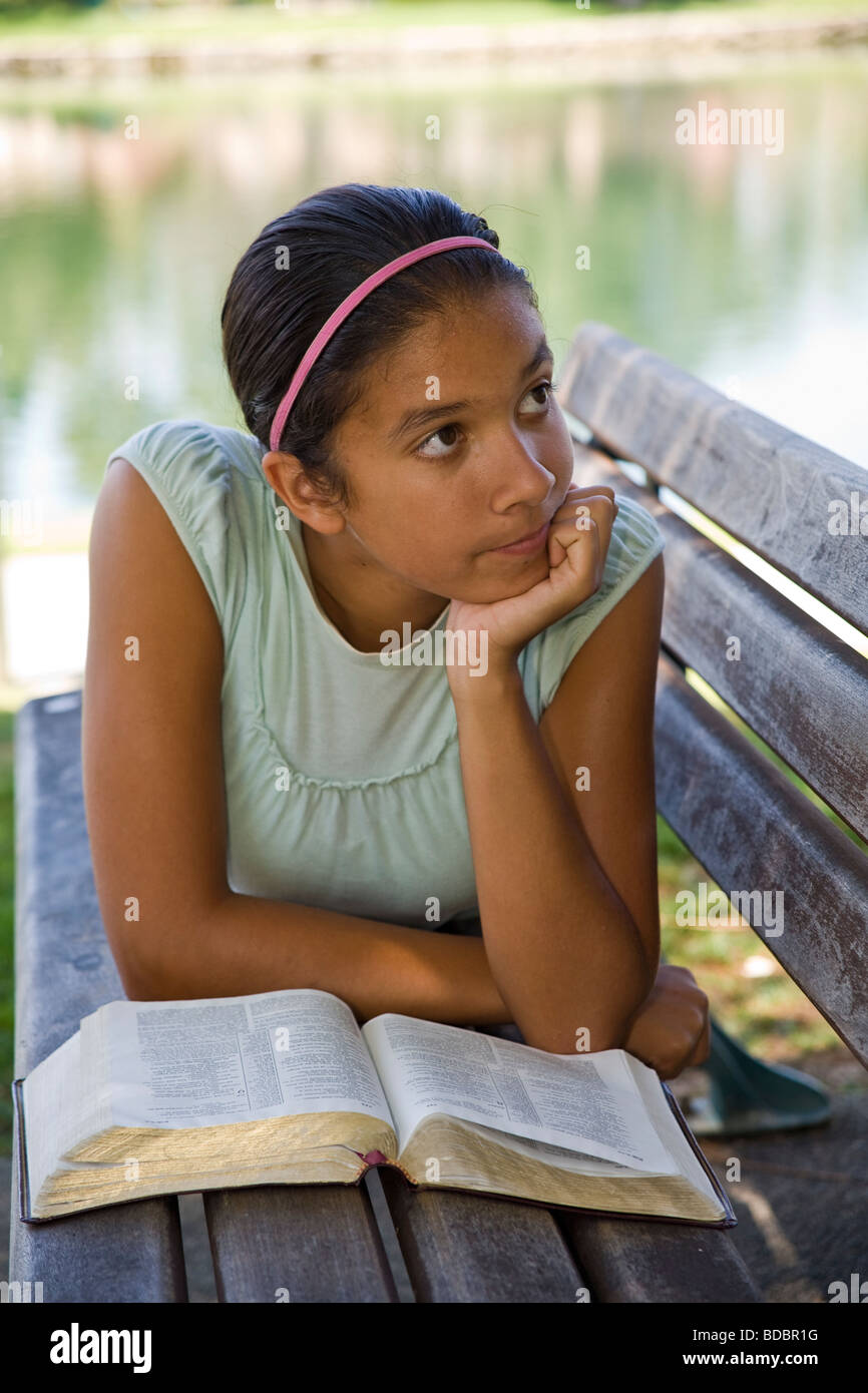 Hispanic/Caucasian girl reading Bible meditating park bench.multi ethnic racial diversity racially diverse multicultural cultural 11-13 year old Myrleen Pearson Stock Photo