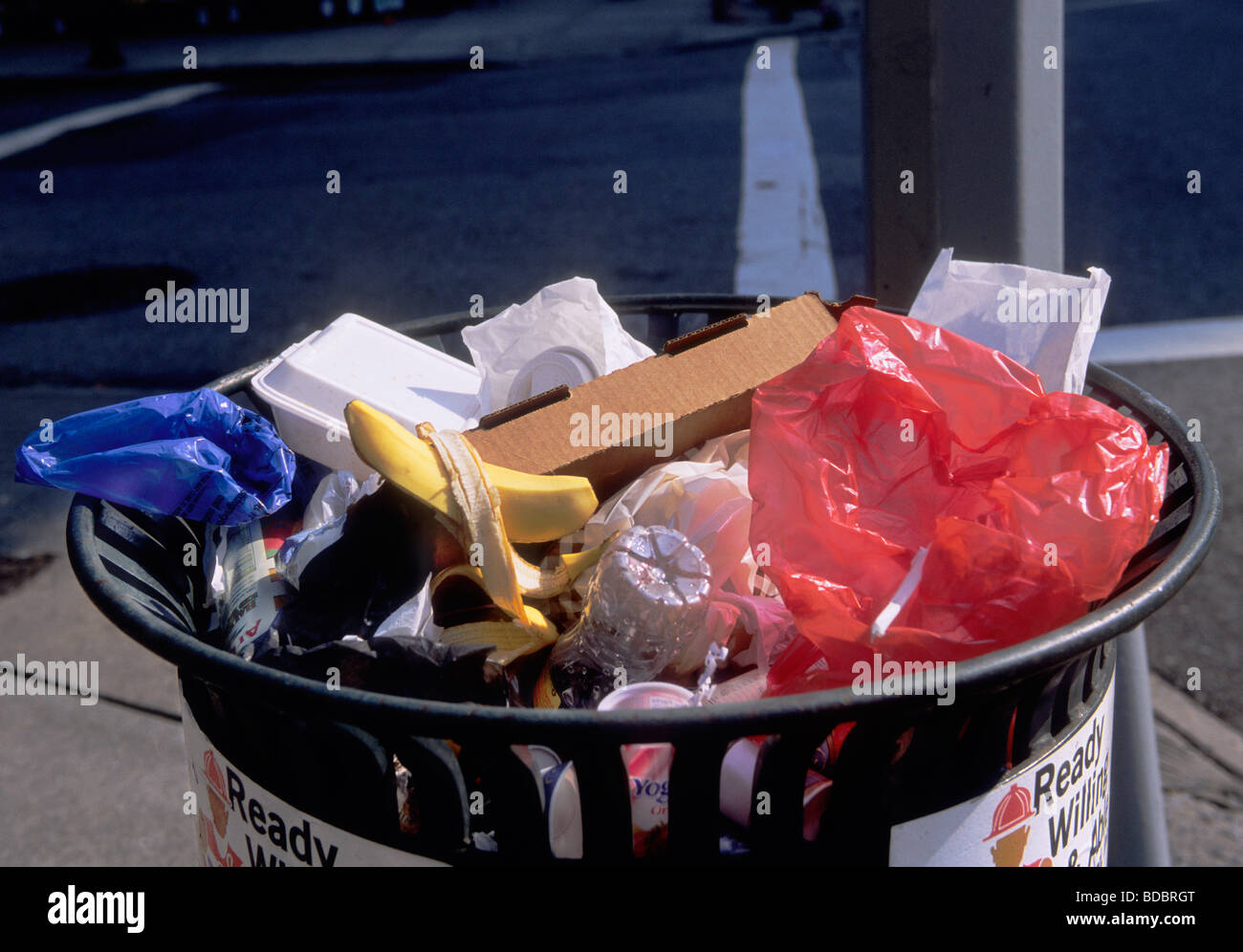 Street trash in trashcan close up. Overflowing garbage bin with recyclable plastic bags and plastic bottles. Stock Photo