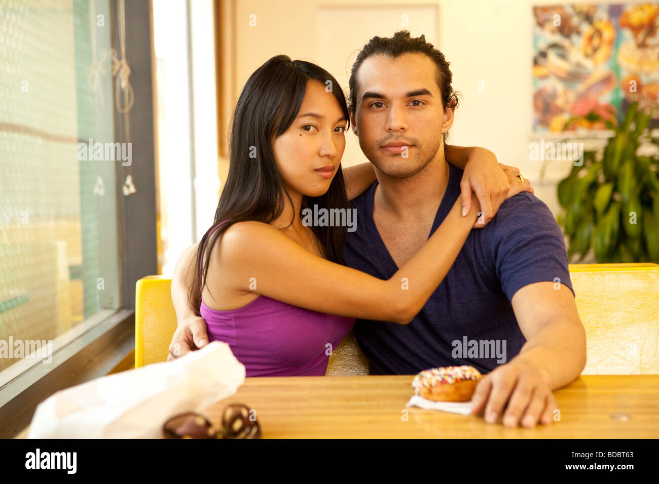 Male Female couple sitting at a table inside a fast food restaurant, looking at camera Stock Photo photo