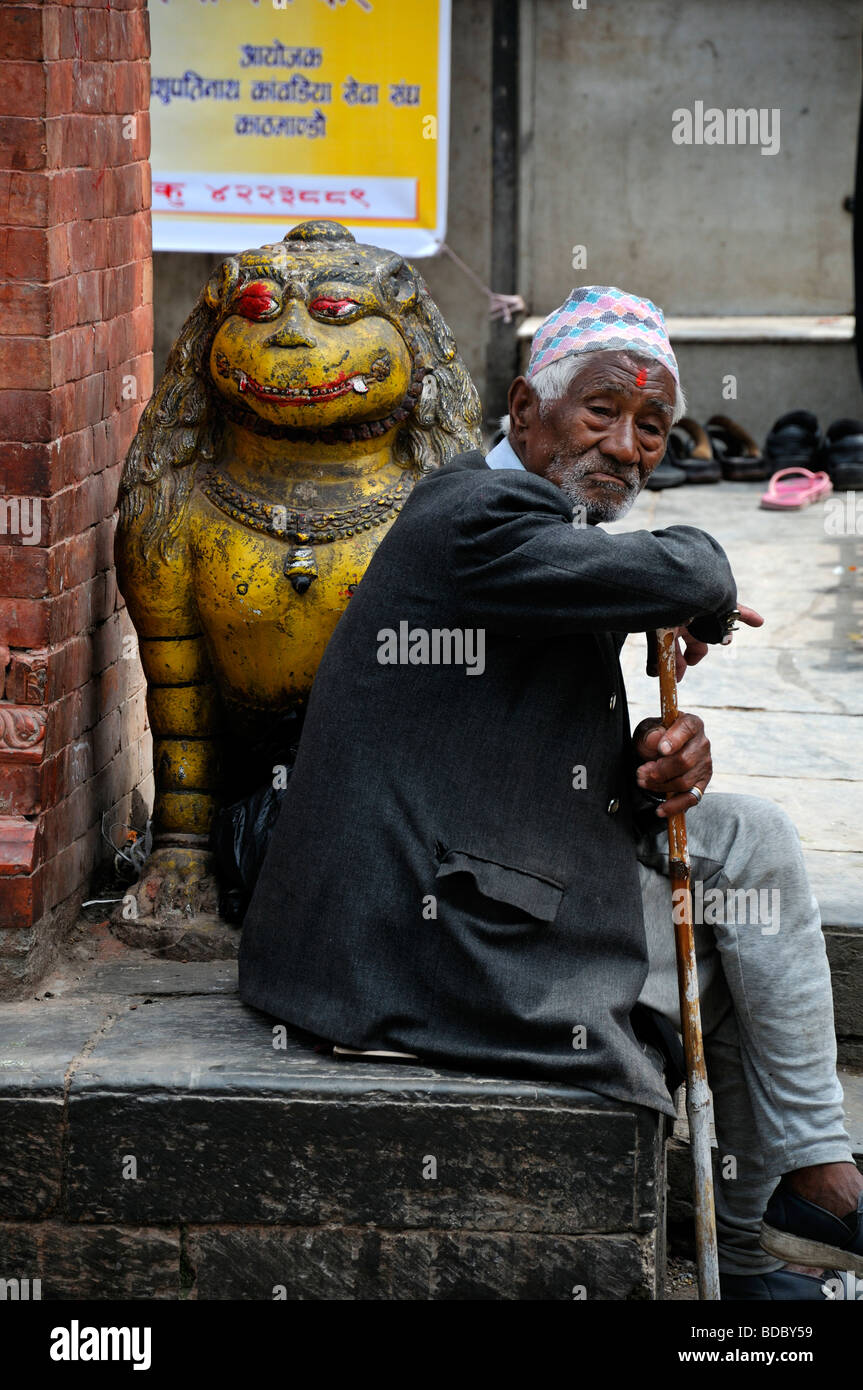 man sitting beside a yellow lion statue in hanuman dhoka durbar square ...