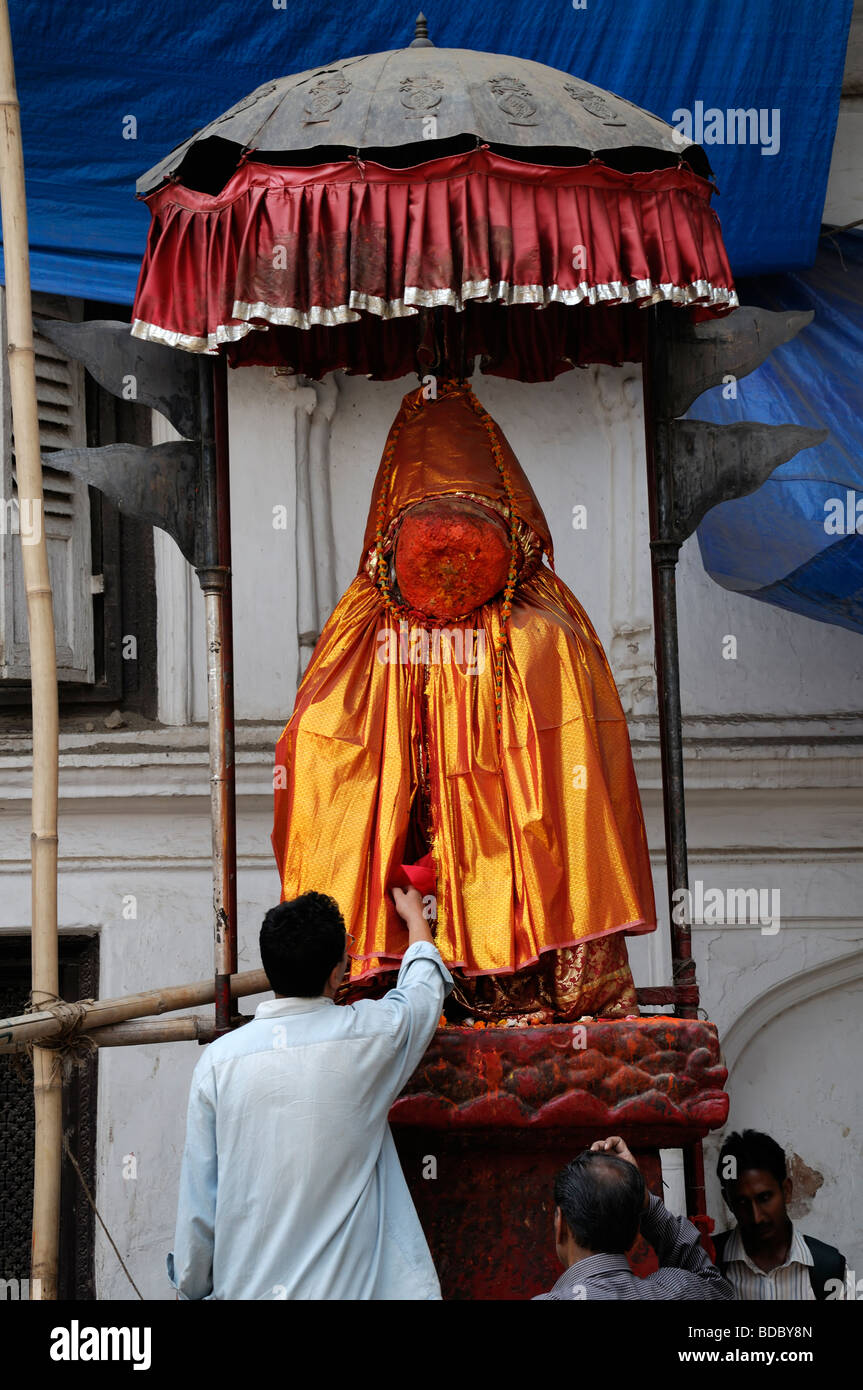 Man touching a statue of Hanuman the Hindu Monkey God, orange ochre silk clothing Hanuman Dhoka durbar square Kathmandu Nepal Stock Photo
