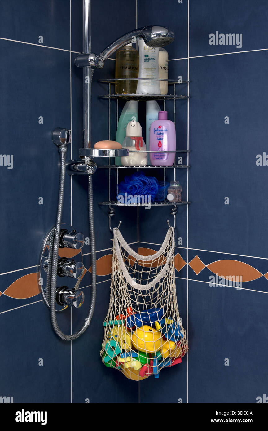 Close up of toiletries and net bag of children's plastic bath toys on steel shower shelves Stock