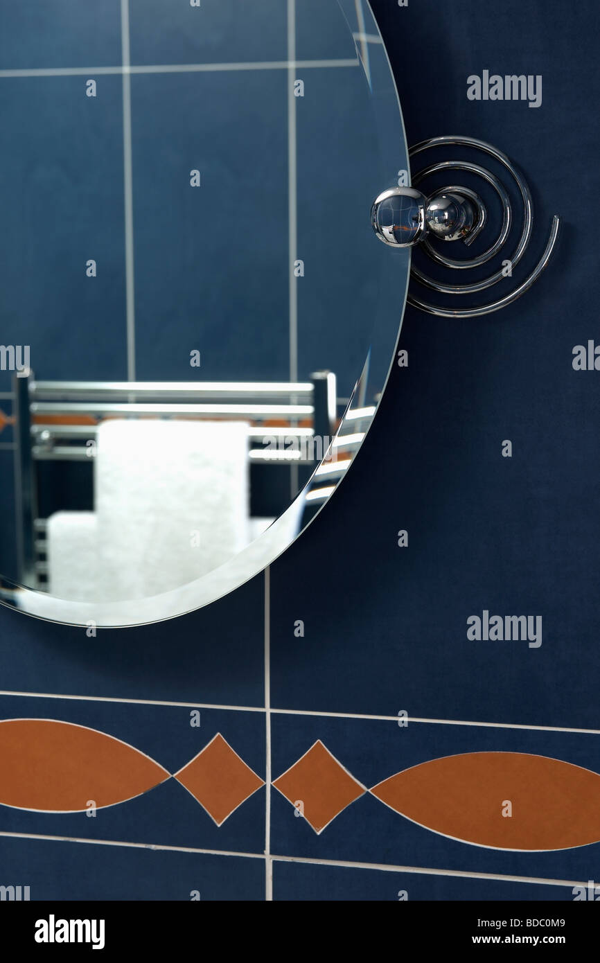 Close up of oval mirror on black tiled wall Stock Photo