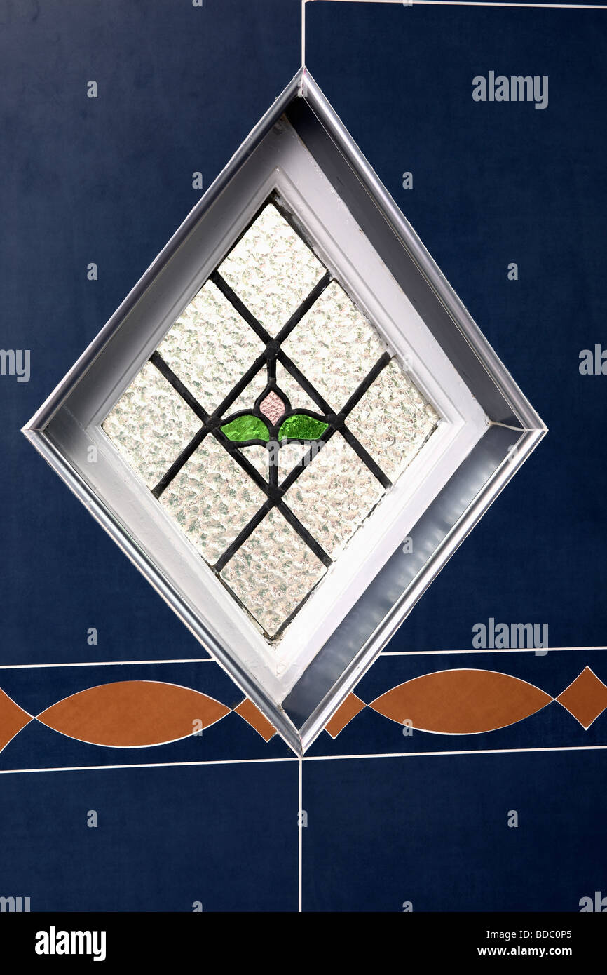 Close up of small diamond shaped stained glass window with flower