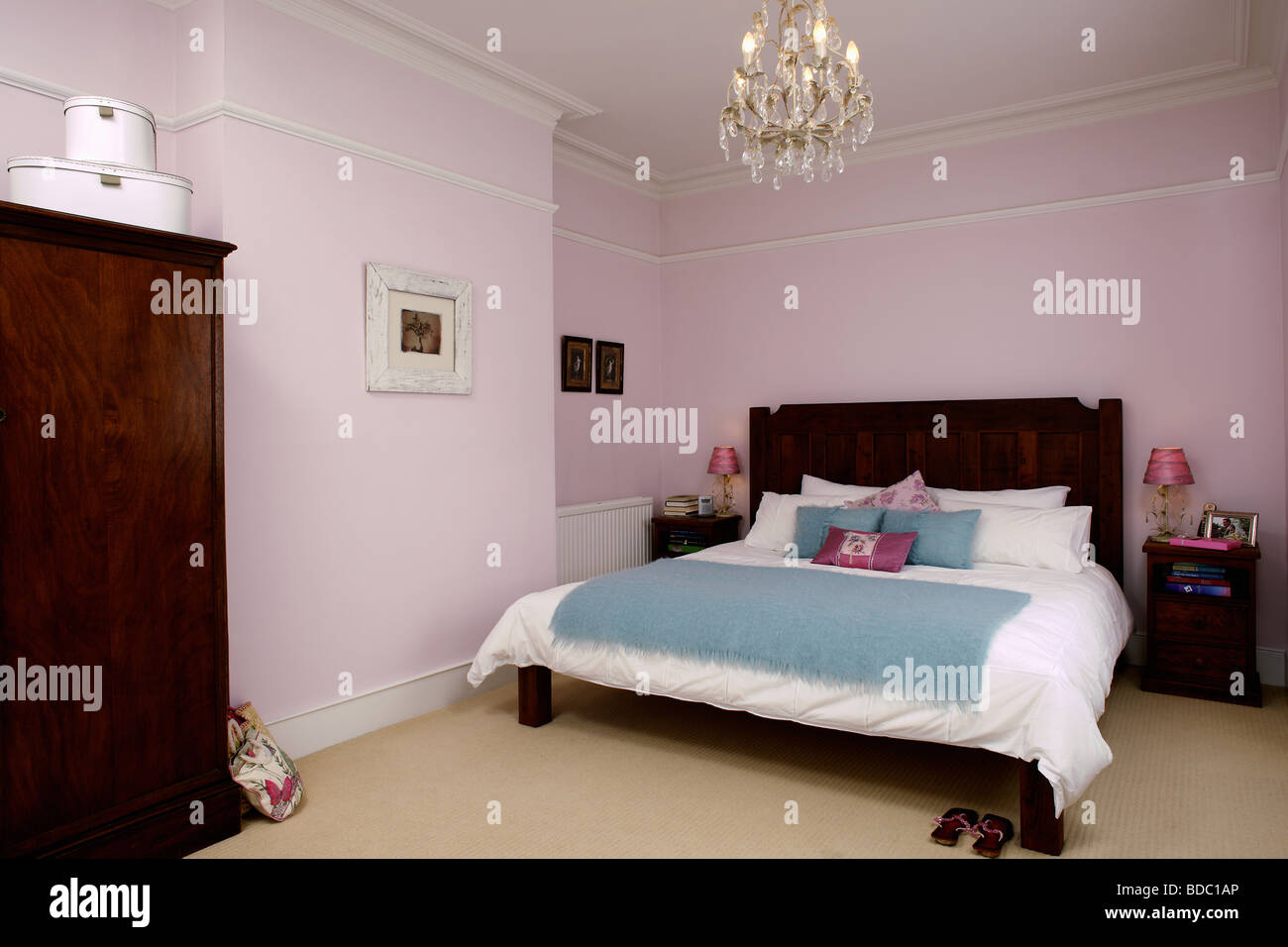 Chandelier Above Dark Wood Bed With White Bed Linen And