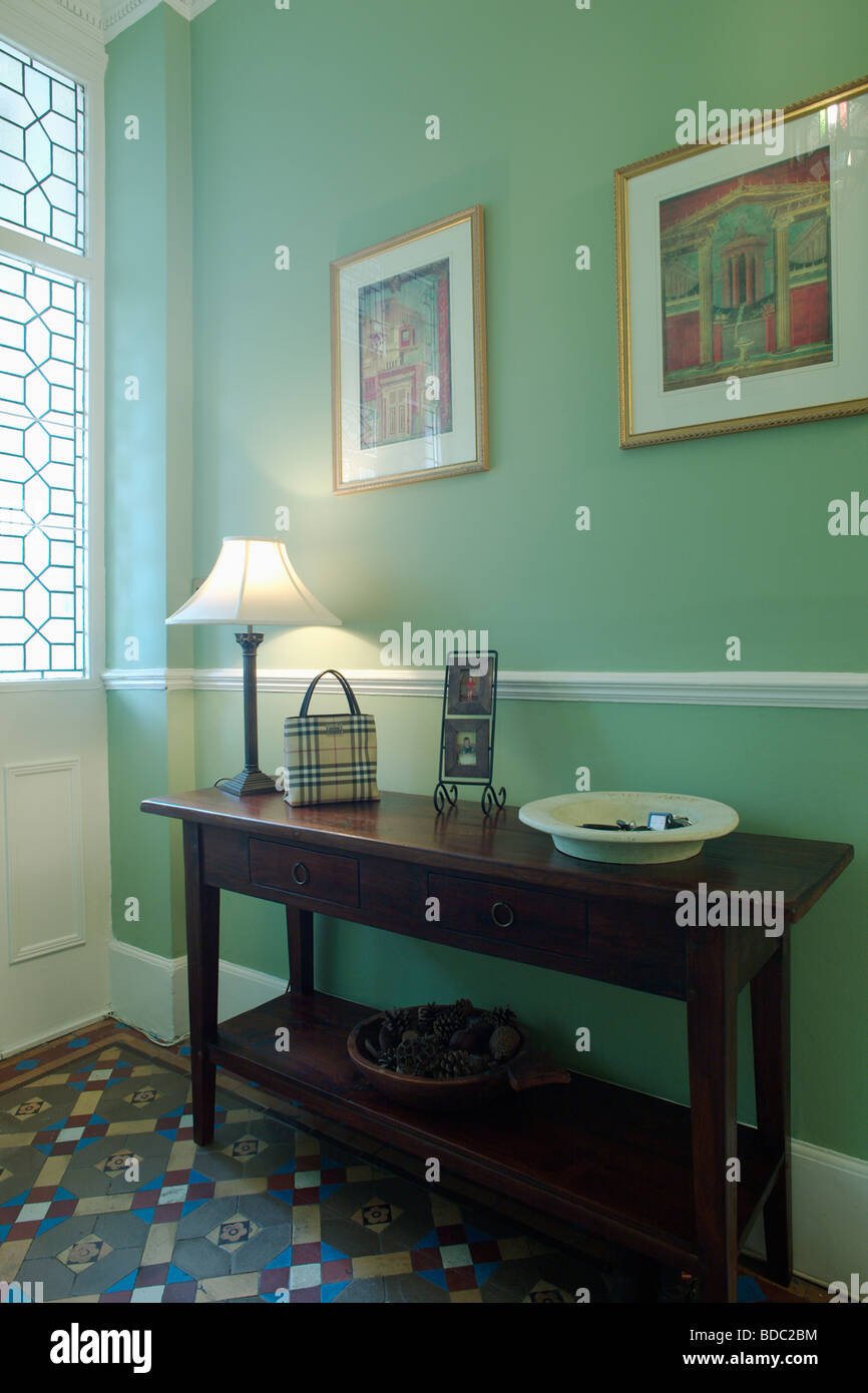 White lamp on console table in green hall with tessellated floor tiles and white dado-rail Stock Photo