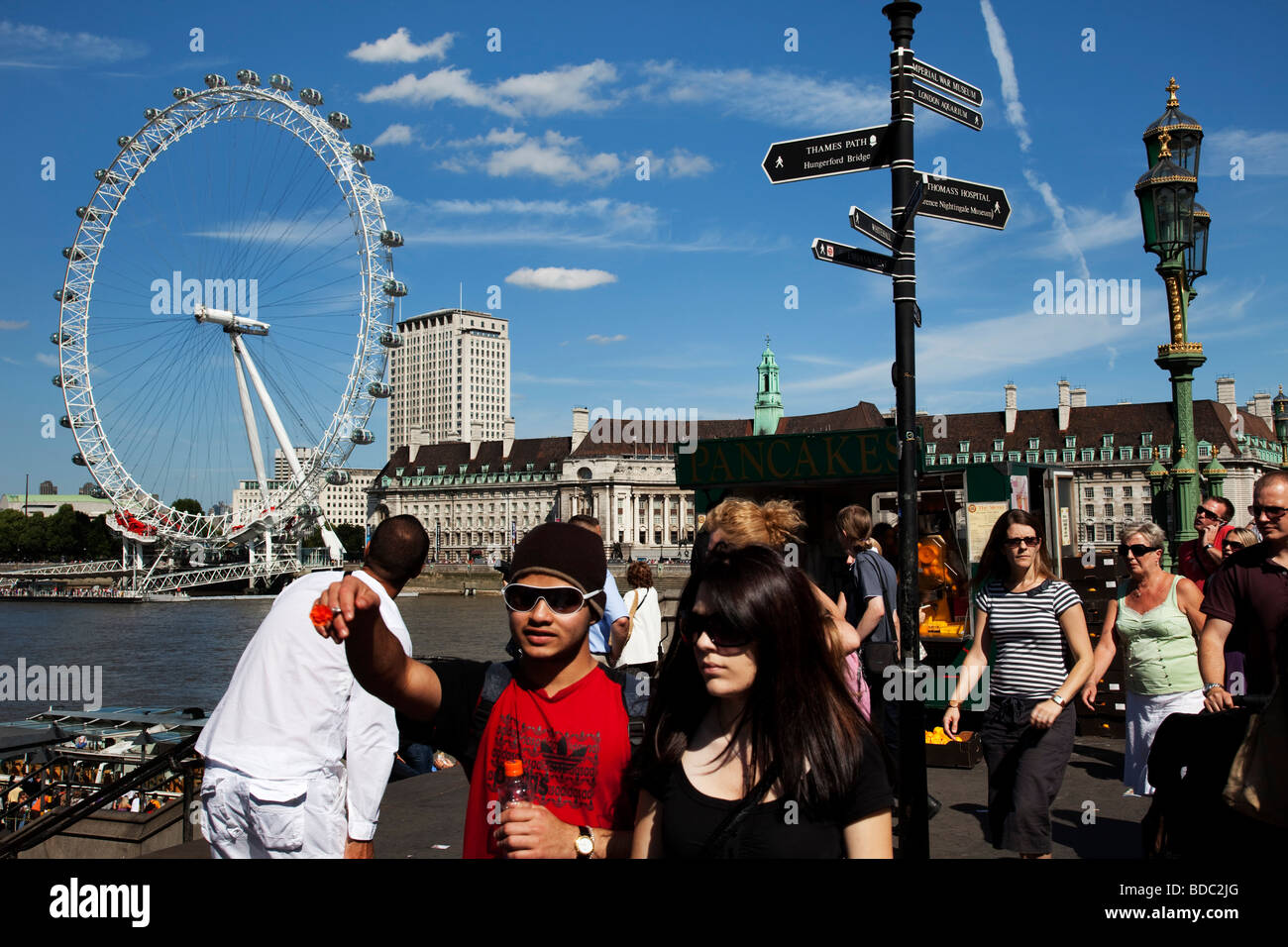 Tourists gather on Westminster Bridge in central London. With the London Eye and other attractions, this is a busy tourism area. Stock Photo