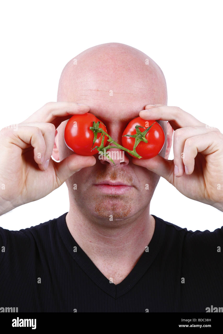 bald headed man has tomatoes in front of his eyes Stock Photo