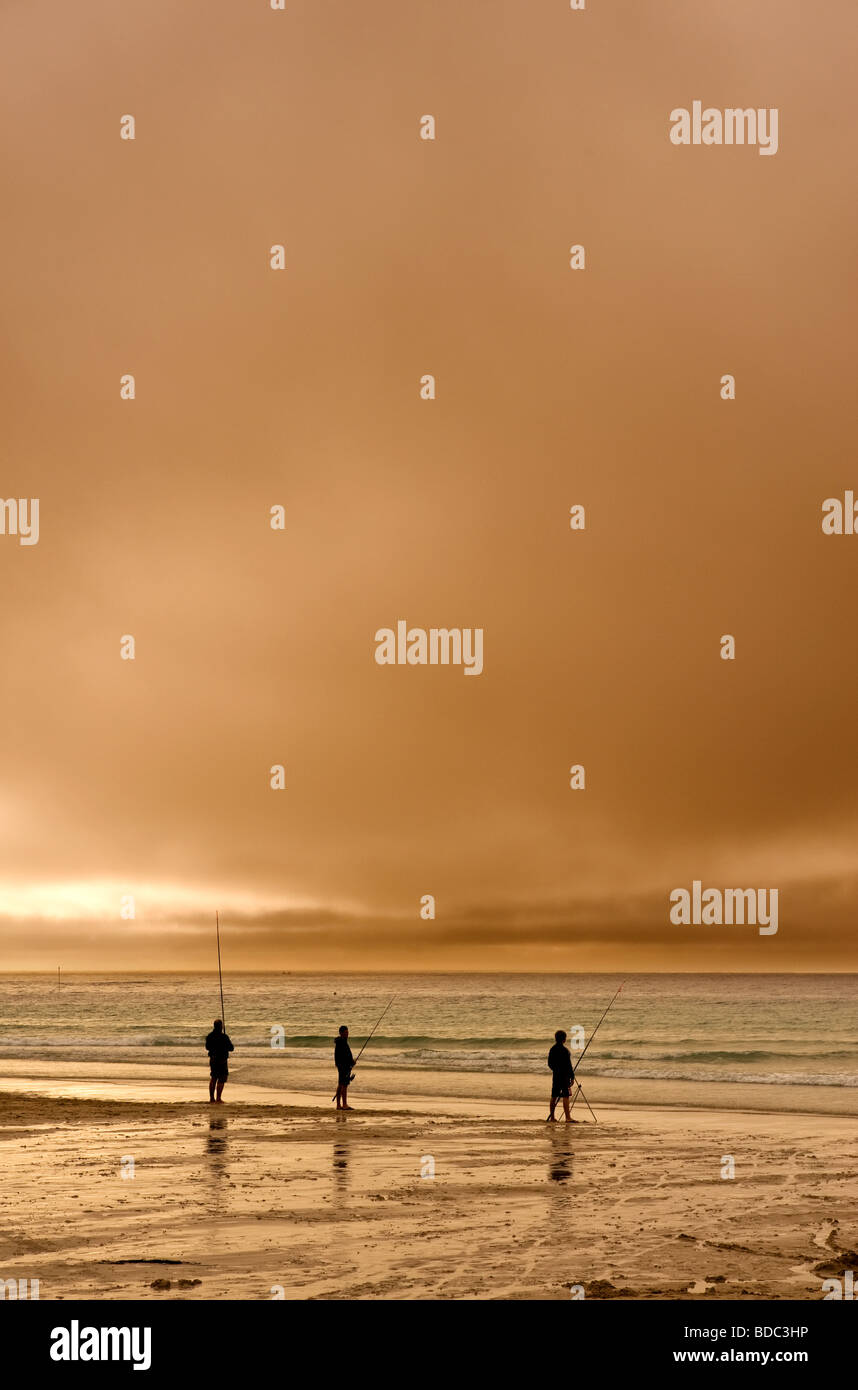 Three anglers beach fishing at sunset in Sennen in Cornwall Stock Photo