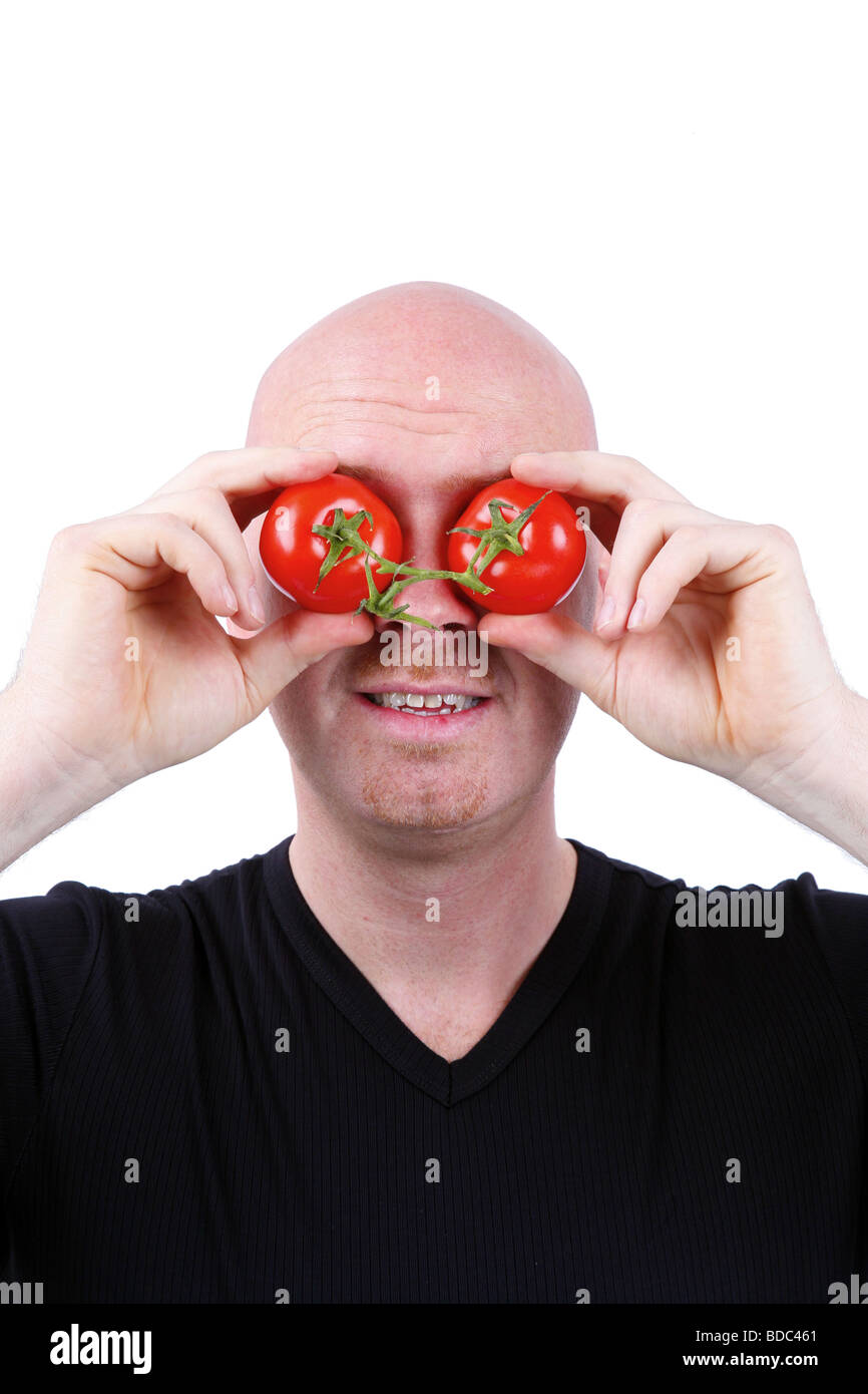 bald headed man has tomatoes in front of his eyes Stock Photo