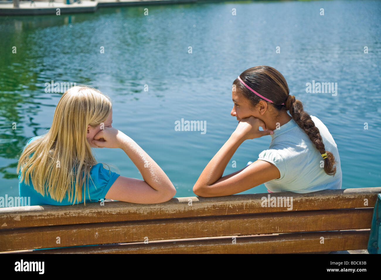 Two Tween tweens girls hang hanging out together Hispanic Caucasian junior high girls sit park bench and have a conversation11-13 year old olds MR Stock Photo