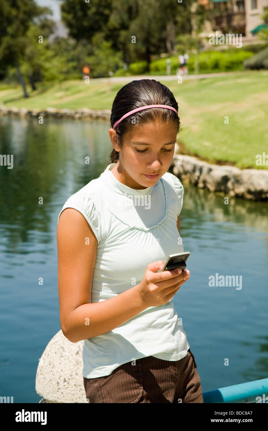 Tween tweens Diverse multi Hispanic girl texting on mobile phone. MR