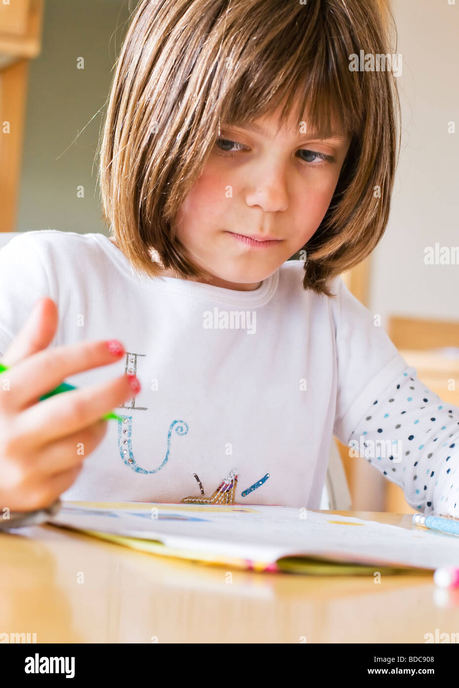 A young girl doing homework sneaks a peek at her fingers to help with her math problem. Stock Photo