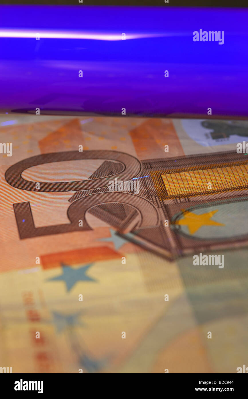 using an ultra violet black light to check a fifty euro banknote to verify that it is genuine Stock Photo