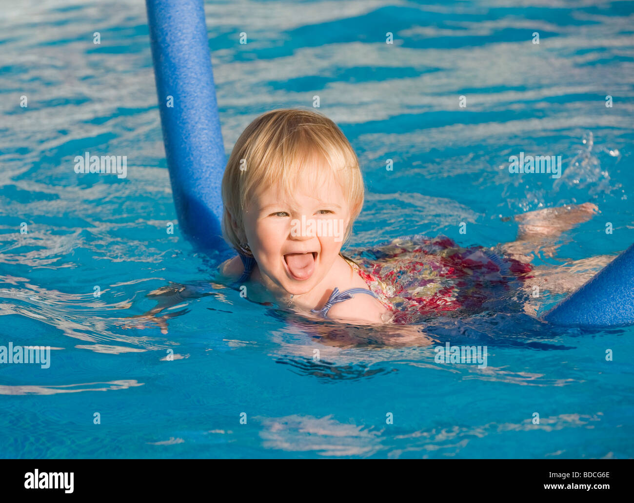 Baby girl learning to swim with aid of a noodle float Stock Photo Alamy